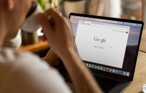 A person drinking coffee while using Google on their laptop
