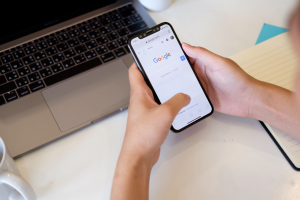 A pair of hands holding a phone with the Google website on the screen