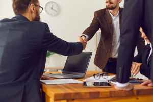 Two people working together shaking hands across the table