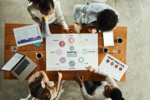 High angle view of team of creative people cooperating while analyzing strategies of digital marketing in the office