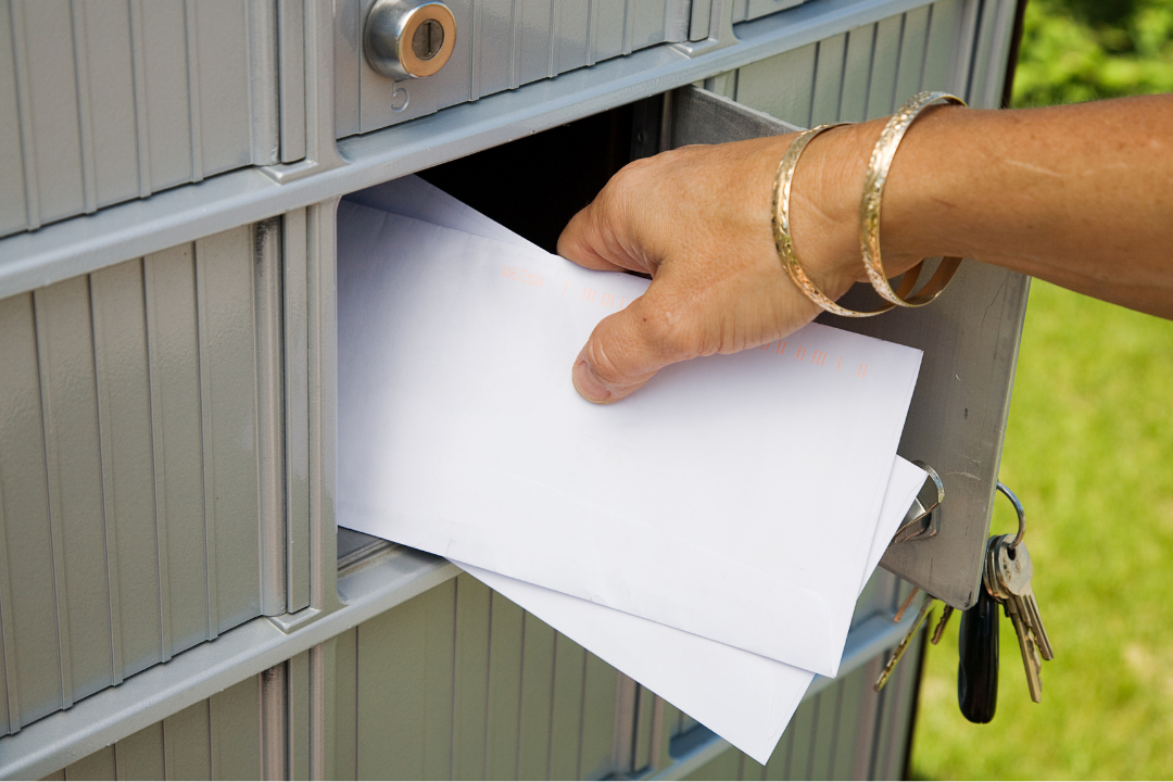 Hand putting two envelopes into a mailbox