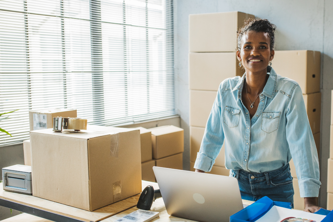 A woman in her office with stacked boxed packages